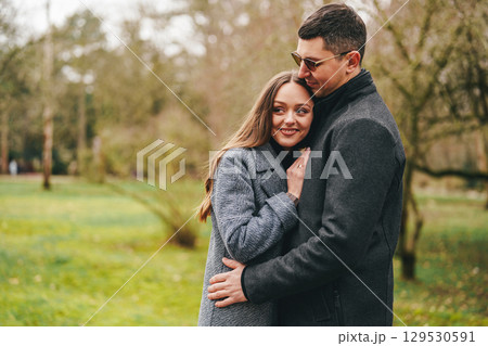 Couple enjoying a warm embrace in a serene park during a sunny autumn day 129530591