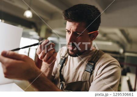 Man organizing tools and materials in a workshop while preparing for a crafting project in the afternoon light 129530661