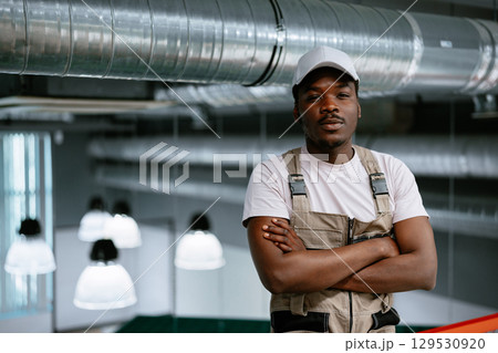 Skilled worker posing confidently in a modern industrial workspace during daytime 129530920