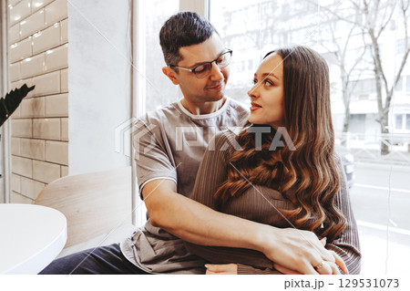 Couple enjoying a cozy moment together in a cafe during a sunny afternoon in an urban setting Couple enjoying a cozy moment together in a cafe during a sunny afternoon in an urban setting 129531073