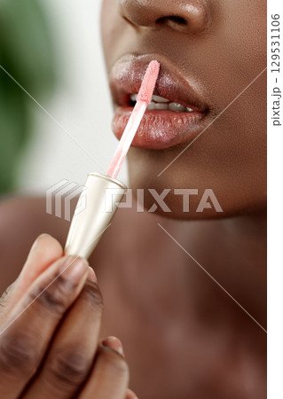 Applying lip gloss to enhance beauty during a self-care routine at home 129531106