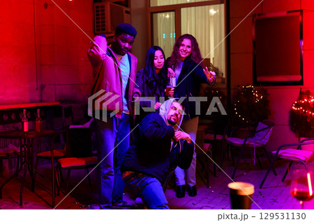 Friends celebrating together at a night gathering in a well-decorated outdoor space with colorful lights Friends celebrating together at a night gathering in a well-decorated outdoor space with colorful lights 129531130