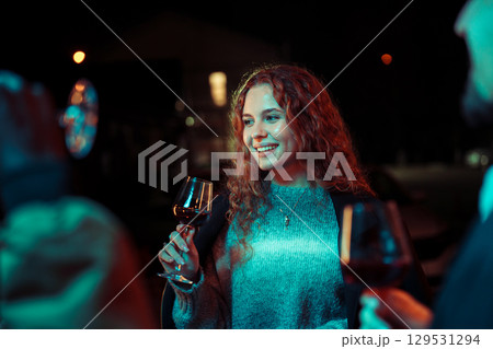Celebration with friends and wine at a lively gathering during a cool evening Celebration with friends and wine at a lively gathering during a cool evening 129531294