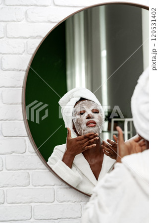 Enjoying a self-care routine with a facial mask in a cozy bathroom setting Enjoying a self-care routine with a facial mask in a cozy bathroom setting 129531402