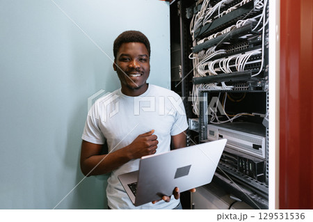 Technician working on network cables in a data center with laptop during daytime Technician working on network cables in a data center with laptop during daytime 129531536