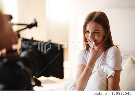 Smiling young woman enjoying a casual conversation during a relaxed indoor filming session on a sunny day 129531546