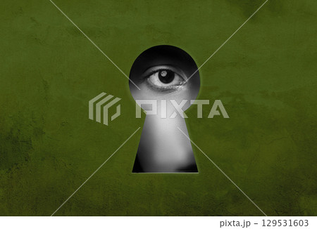 Mysterious gaze through a keyhole revealing an eye watching the world in a dimly lit environment 129531603