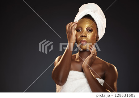 Woman applying gold facial mask in spa setting during evening relaxation session Woman applying gold facial mask in spa setting during evening relaxation session 129531605