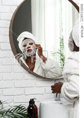 Enjoying a relaxing skincare routine with a facial mask in a bright bathroom Enjoying a relaxing skincare routine with a facial mask in a bright bathroom 129531608