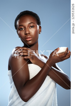 Woman applying skin cream during a skincare routine with a soft towel in a calming studio environment 129531626