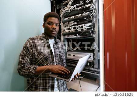 Young technician working on network server in data center during afternoon 129531629