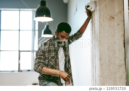 Young man inspecting a security camera in a modern workspace during the day 129531720