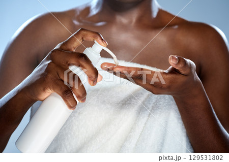 Woman applying lotion in a bathroom setting during morning skincare routine 129531802