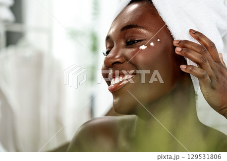 Woman applying skincare product in bright bathroom during morning routine for healthy skin and self-care Woman applying skincare product in bright bathroom during morning routine for healthy skin and self-care 129531806
