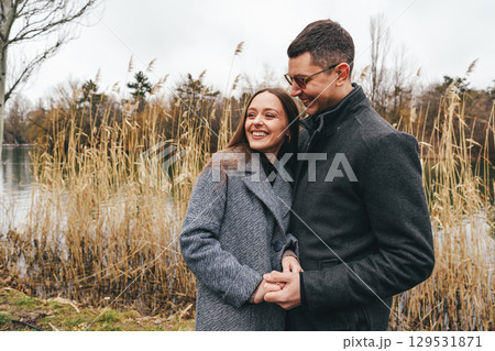 Couple enjoys a romantic moment by the lakeside during a cloudy day in autumn Couple enjoys a romantic moment by the lakeside during a cloudy day in autumn 129531871