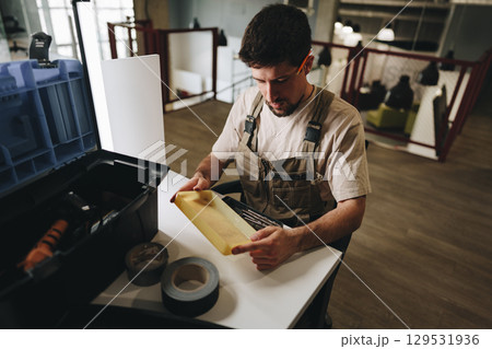 Man organizing tools and materials in a workshop while preparing for a crafting project in the afternoon light Man organizing tools and materials in a workshop while preparing for a crafting project in the afternoon light 129531936