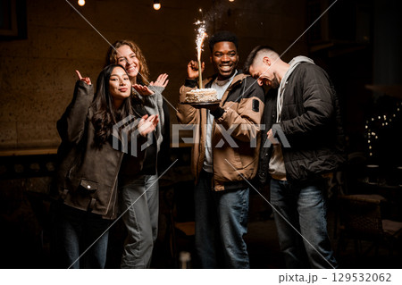 Friends celebrate together with cake and sparklers during a joyful evening gathering in an outdoor setting 129532062