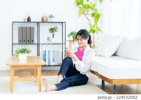 部屋でスマホを操作する若い女性 部屋でスマホを操作する若い女性 129532082