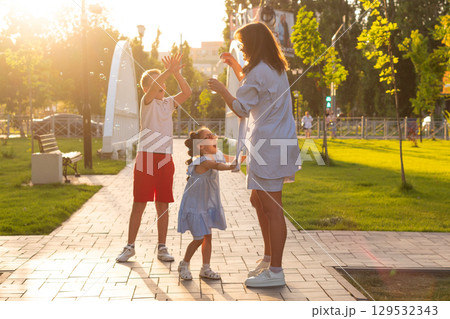 Kids chase bubbles as mother blows at sunset park Kids chase bubbles as mother blows at sunset park 129532343