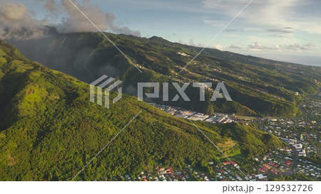 Breathtaking scenery of Tahiti tropical island, French Polynesia. Lush green mountains canyon, green forest hills, houses, buildings, village cityscape under cloudy blue sky. Aerial drone panorama Breathtaking scenery of Tahiti tropical island, French Polynesia. Lush green mountains canyon, green forest hills, houses, buildings, village cityscape under cloudy blue sky. Aerial drone panorama 129532726