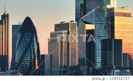 United Kingdom, London: Warm sunset light illuminating the modern skyscrapers of London's financial district, including 30 St Mary Axe (The Gherkin), creating a stunning cityscape. Drone flight footag United Kingdom, London: Warm sunset light illuminating the modern skyscrapers of London's financial district, including 30 St Mary Axe (The Gherkin), creating a stunning cityscape. Drone flight footag 129532737