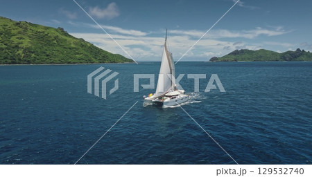 Luxurious catamaran sailing in the pristine waters of Fiji, near Kuata island, offering a breathtaking view of the tropical landscape and the vastness of the Pacific Ocean. Drone flight 129532740