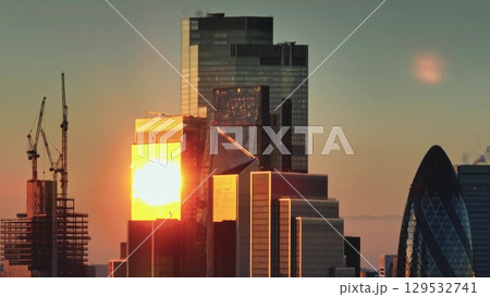 Modern glass skyscrapers in London financial district at golden hour. Sunset light reflecting on glass facades of buildings. Cityscape skyline background. Panorama shot Modern glass skyscrapers in London financial district at golden hour. Sunset light reflecting on glass facades of buildings. Cityscape skyline background. Panorama shot 129532741