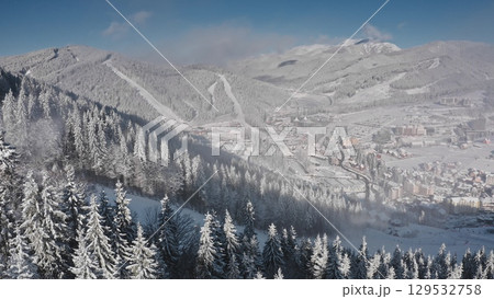 Drone capturing a breathtaking panorama of snow covered slopes, pine forests, and the charming town of Bukovel in Ukraine, a popular winter sports destination. Winter wild nature travel background Drone capturing a breathtaking panorama of snow covered slopes, pine forests, and the charming town of Bukovel in Ukraine, a popular winter sports destination. Winter wild nature travel background 129532758