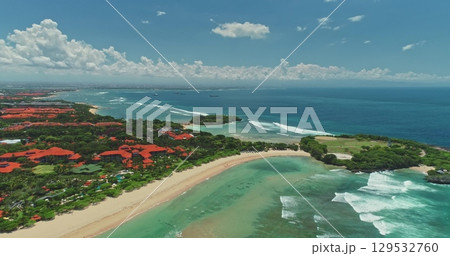 Aerial drone of Nusa Dua beach with luxury hotels, white sand, turquoise water and waves meeting the blue of the Indian Ocean, Bali, Indonesia, on a sunny day with some clouds 129532760