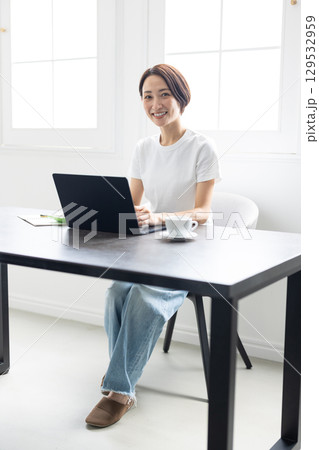 明るい自宅でノートパソコンを使ってテレワークする女性 129532959