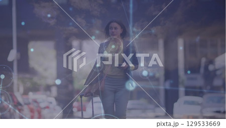 Network of connections over caucasian businesswoman with trolley bag walking on the street 129533669