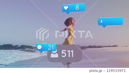 Image of social media icons and numbers on banners over woman running on beach 129533971