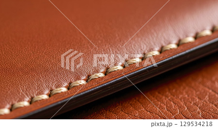 Macro closeup of brown leather texture with neat stitching. Concept of handmade craftsmanship, quality materials and luxury goods with fine expensive details 129534218