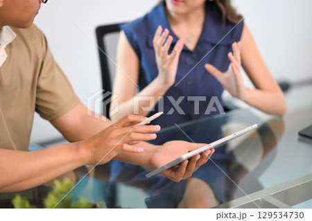 Close up of a team brainstorming over a digital tablet in a modern office Close up of a team brainstorming over a digital tablet in a modern office 129534730
