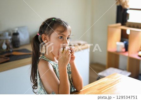 Little child eating a homemade sandwich in a cozy kitchen 129534751