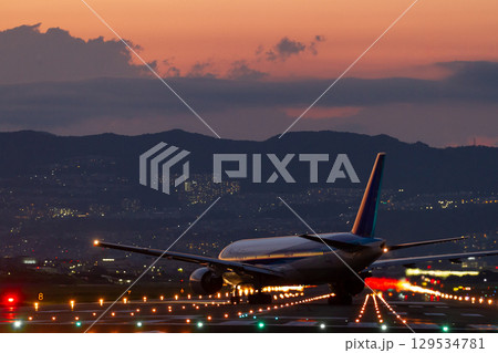 夕暮れの滑走路で進行方向を変える旅客機の姿 129534781