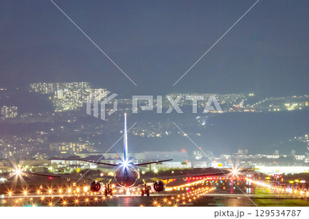 輝く誘導灯と離陸前の旅客機 129534787