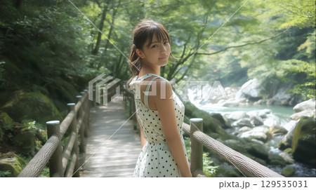 夏の渓流沿いの遊歩道に立つ若い日本人女性 129535031