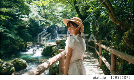 夏の渓流沿いの遊歩道に立つ若い日本人女性 129535073