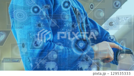 Pointing man in blue jacket checking smartwatch in modern office, with digital interface elements Pointing man in blue jacket checking smartwatch in modern office, with digital interface elements 129535333