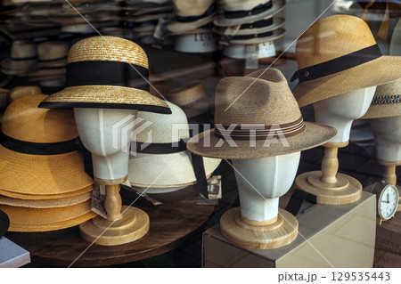 Straw hats displayed on mannequin heads in a storefront window. Fashion accessories, summer style, small business retail, craftsmanship Straw hats displayed on mannequin heads in a storefront window. Fashion accessories, summer style, small business retail, craftsmanship 129535443