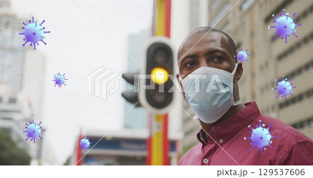 Image of virus cells over african american man wearing face mask 129537606