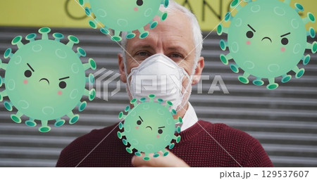 Image of falling covid 19 cells over senior caucasian man wearing face mask 129537607