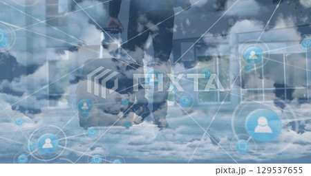 Image of network of profile icons over clouds against businessman walking with a trolley bag Image of network of profile icons over clouds against businessman walking with a trolley bag 129537655