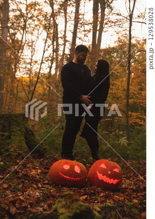 Couple in Autumn Forest with Halloween Pumpkins Couple in Autumn Forest with Halloween Pumpkins 129538028