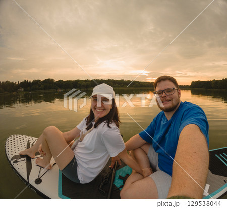 Couple Paddleboarding at Sunset 129538044