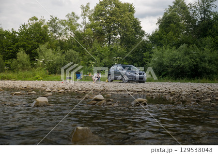 Camping by the River with SUV and Campfire 129538048