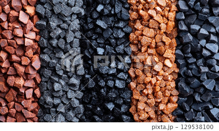 Rows of mineral gravel in vibrant shades of red black and orange display unique textures. arrangement highlights natural beauty of materials and their potential uses in landscaping. 129538100
