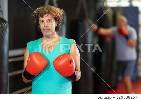 Strong man practicing punches on punching bag. Boxing training Strong man practicing punches on punching bag. Boxing training 129538257