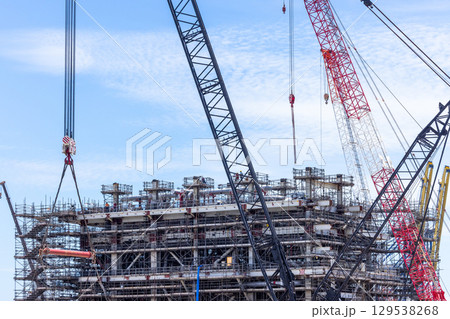 Construction site with construction crawler cranes and multi storey unfinished buildings, Many high rise cranes and industrial construction equipment, Contruction site bl;ue sky background. 129538268